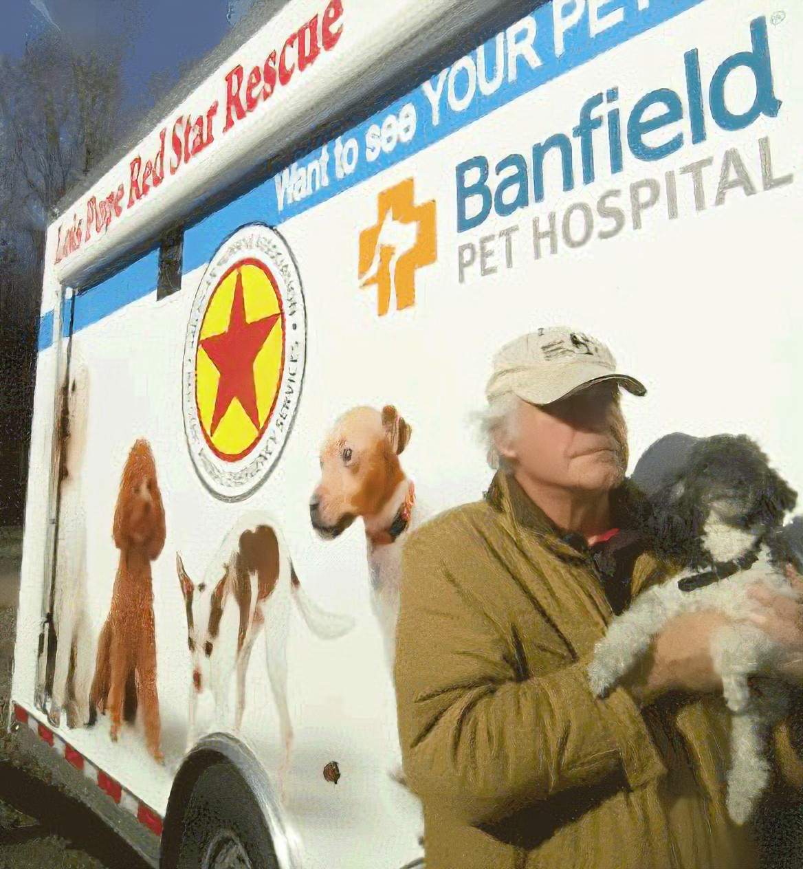 A person carrying a dog next to a rescue vehicle